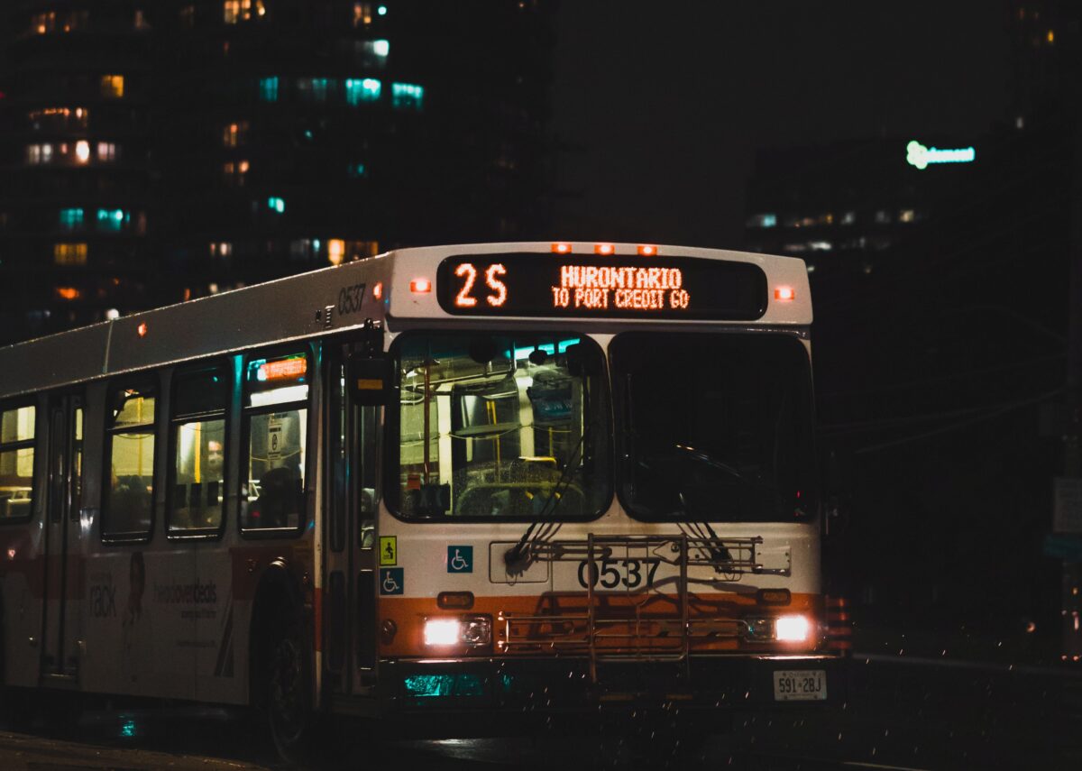orange and white bus in front of an apartment building at night